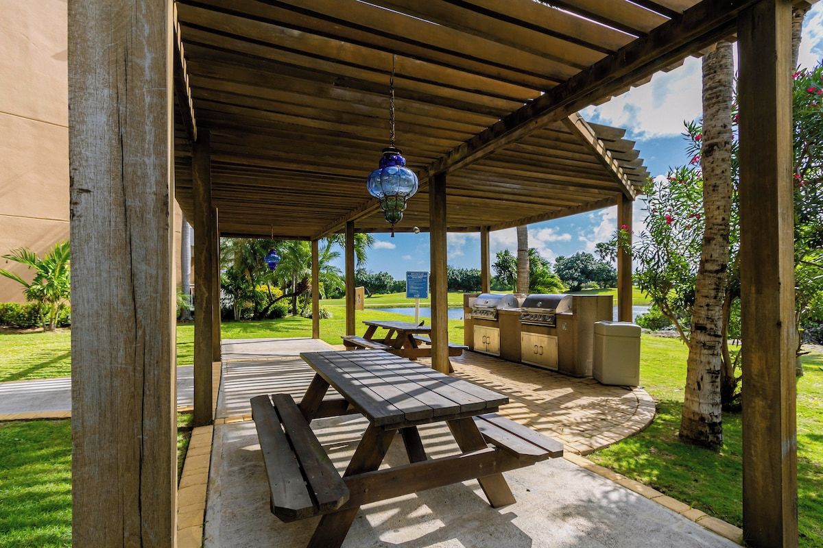 Une terrasse extérieure avec des tables de pique-nique et un barbecue.