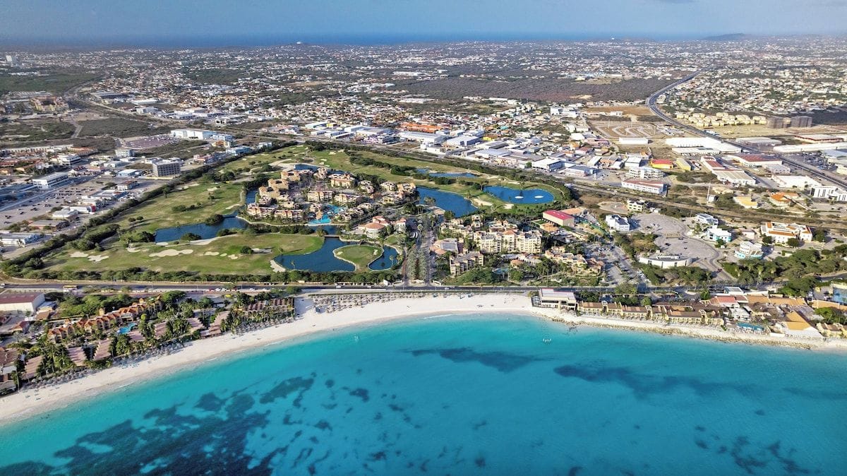 Eine Luftaufnahme einer Küstenstadt mit Strand, Golfplatz und Wohngebieten.