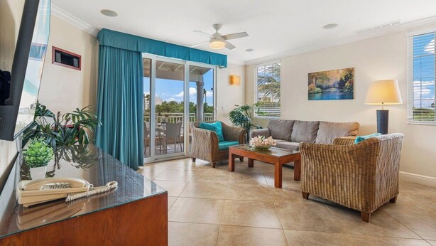 A spacious living area with a glass partition, a sofa, a wicker chair, a coffee table, and a telephone on a desk. - Divi Aruba: 3BR Oasis w Free Parking near Beaches (Oranjestad)