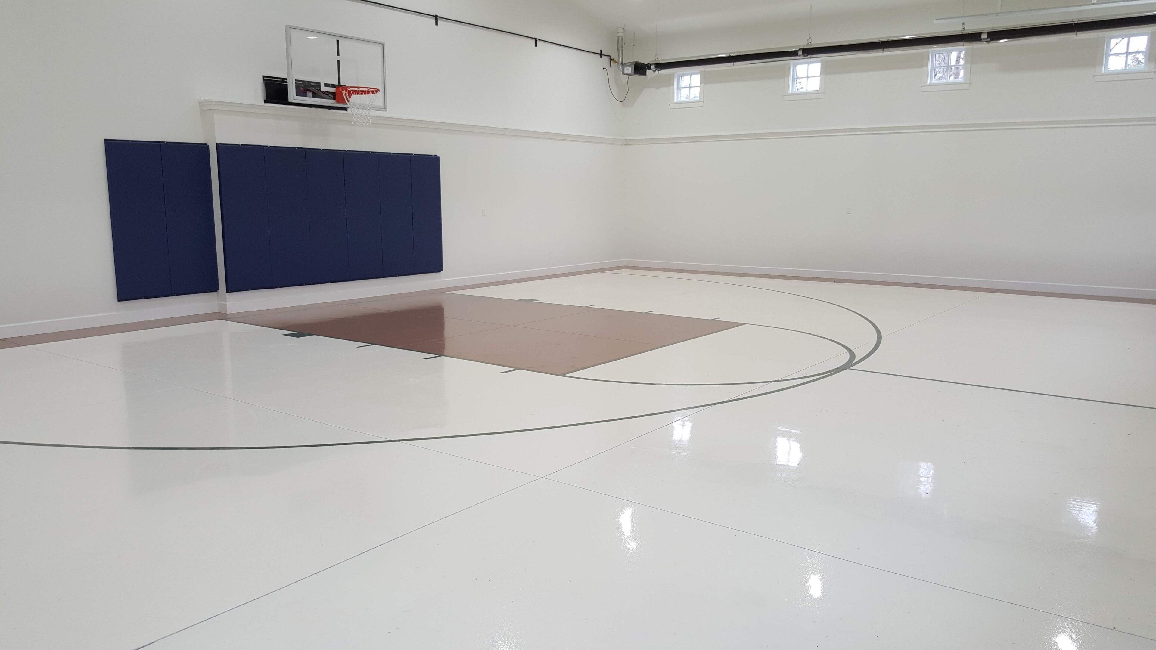 Un terrain de basket-ball équipé d’un panier, d’un mur rembourré et d’une zone de jeu au sol également rembourrée.