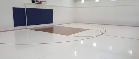 Un terrain de basket-ball équipé d’un panier, d’un mur rembourré et d’une zone de jeu au sol également rembourrée.