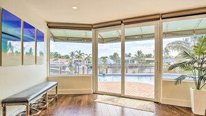 A room with a bench, large sliding glass doors, a view of a swimming pool, and a potted plant. - 1 Mi to Pompano Beach: Vacation Rental w/ Pool! (Pompano Beach)