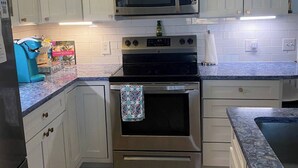 A kitchen with white cabinets, a stainless steel microwave, an oven, and a granite countertop. - Mad Mahi Canal with pool.<br>This is a pet friendly home. A pet fee and approval of your pet is required. (Summerland Key)