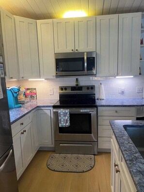 Kitchen features a gas range, microwave, and stainless steel range hood.