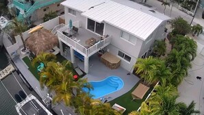 A two-story house with a swimming pool, a balcony, and a patio area with outdoor furniture. - Mad Mahi Canal with pool.<br>This is a pet friendly home. A pet fee and approval of your pet is required. (Summerland Key)