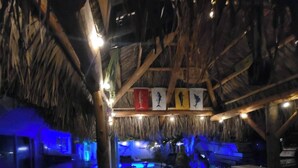 An indoor space with a thatched roof, wooden beams, and a seating area with tables and chairs. - Mad Mahi Canal with pool.<br>This is a pet friendly home. A pet fee and approval of your pet is required. (Summerland Key)