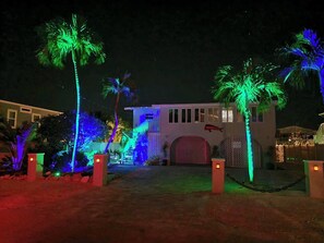 Stunning entrance with a prominent red door, palm trees, and a decorative fish sculpture.