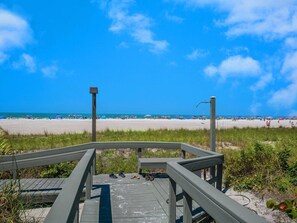 A wooden boardwalk leading to a beach with a clear sky.