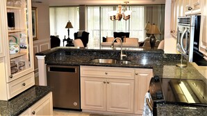 A modern kitchen with granite countertops, stainless steel appliances, and light wood cabinetry.