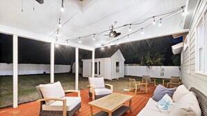 Une terrasse extérieure avec des meubles en bois, des guirlandes lumineuses et un espace abrité.