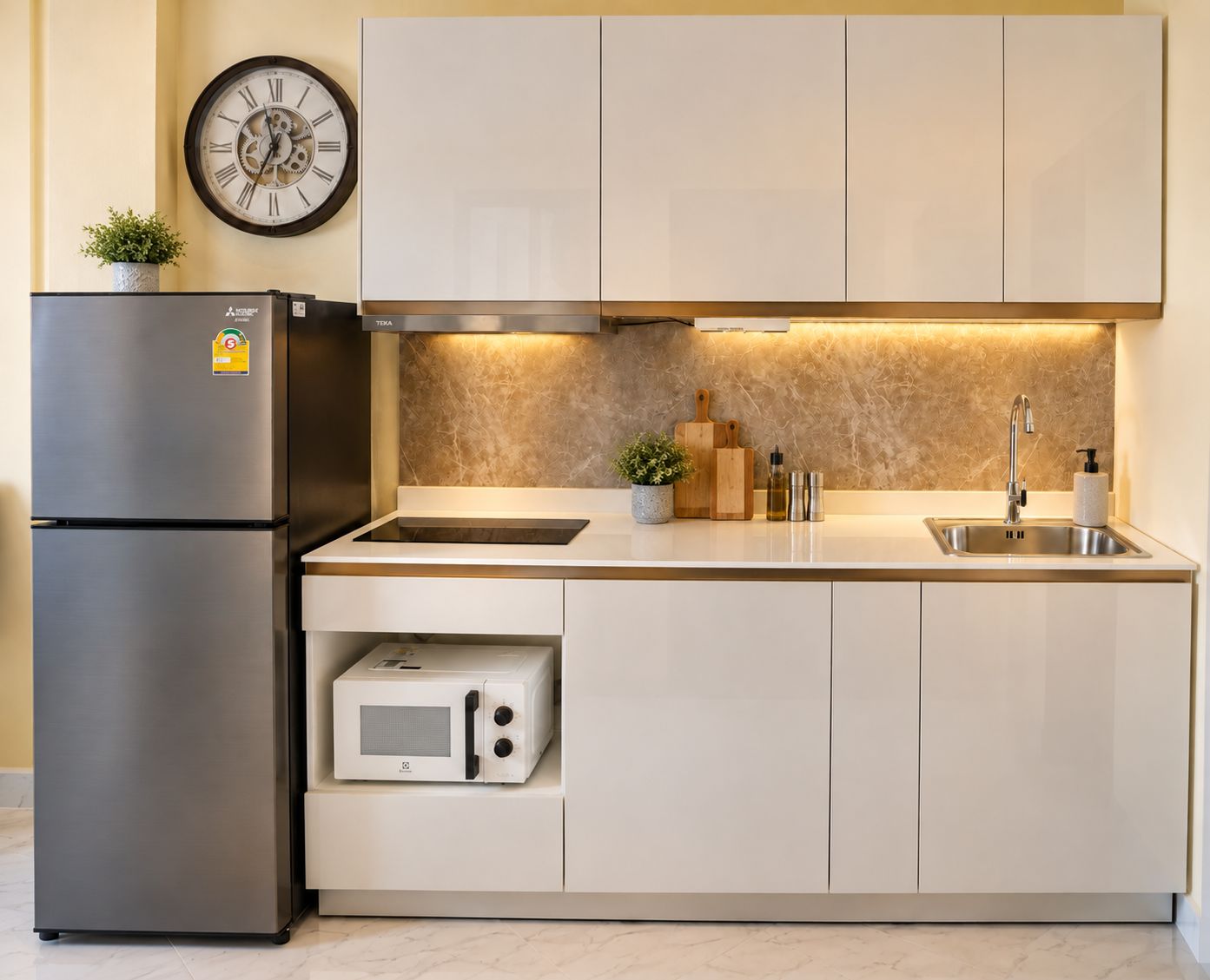 A modern kitchen with a built-in refrigerator, microwave, and a stainless steel sink.