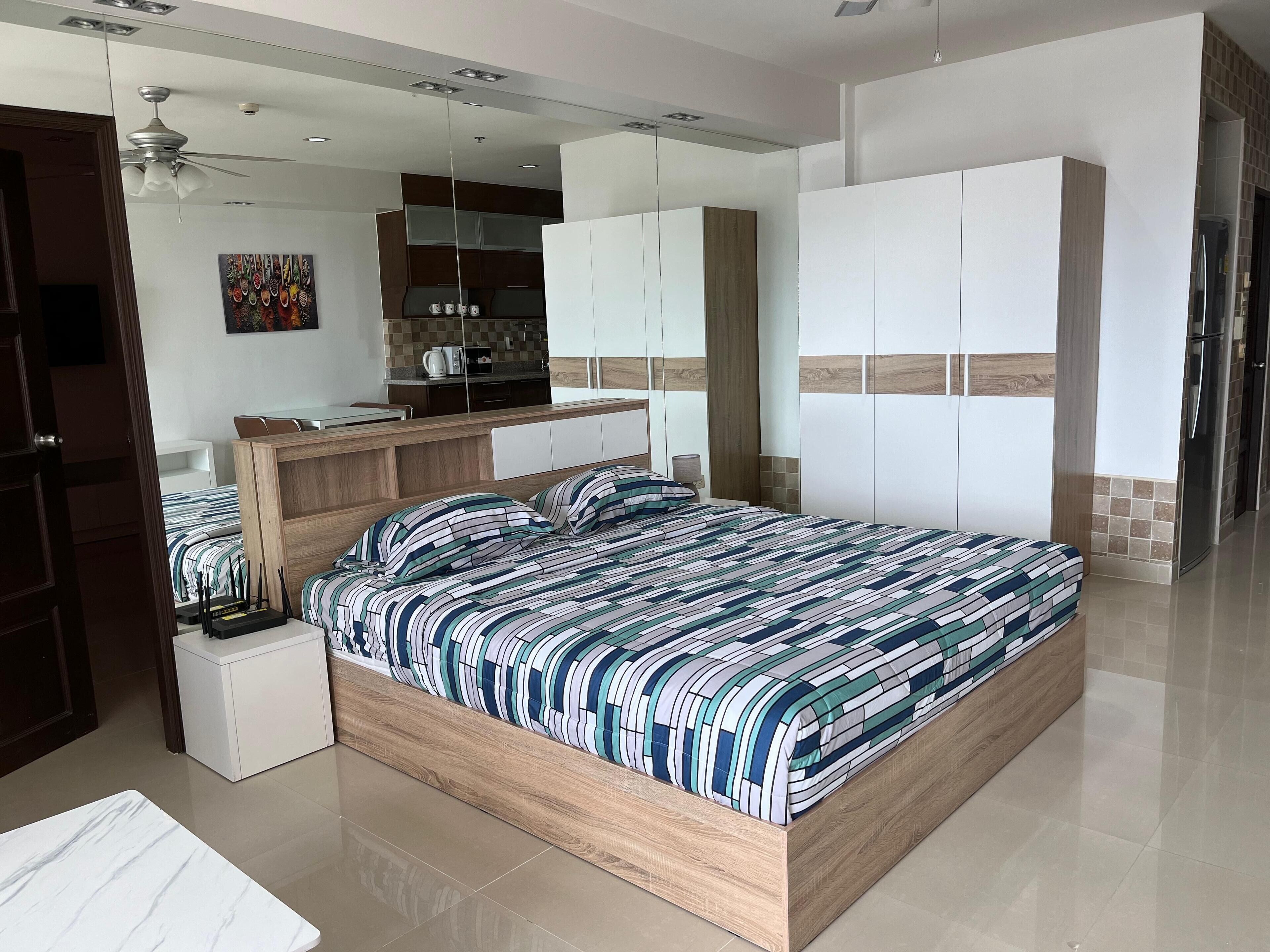 Une chambre moderne avec un grand lit, un bureau intégré et un coin cuisine.