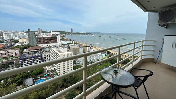 Varanda com mesa e cadeiras, vista para a cidade e para a praia.