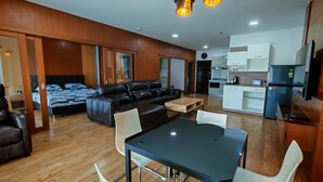 Quarto de hotel moderno com sofá, mesa de jantar e cozinha.