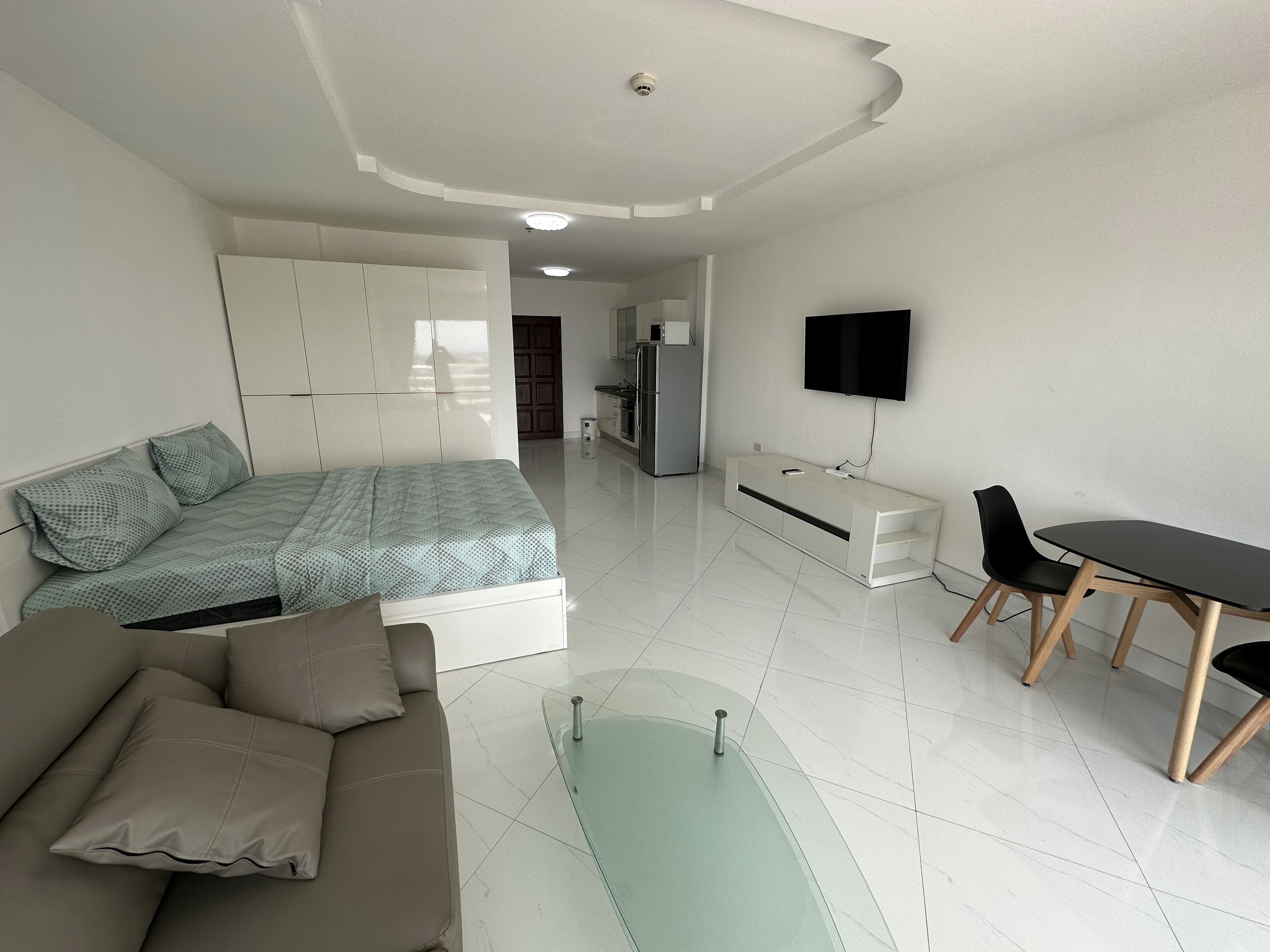 Un dormitorio moderno con cama, sofá, televisión y escritorio.