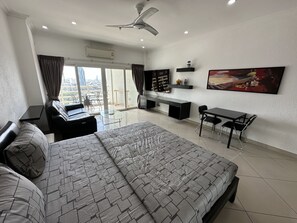 A modern bedroom with a bed, a desk, and a TV. - Condo Express View Talay 6 (Pattaya)