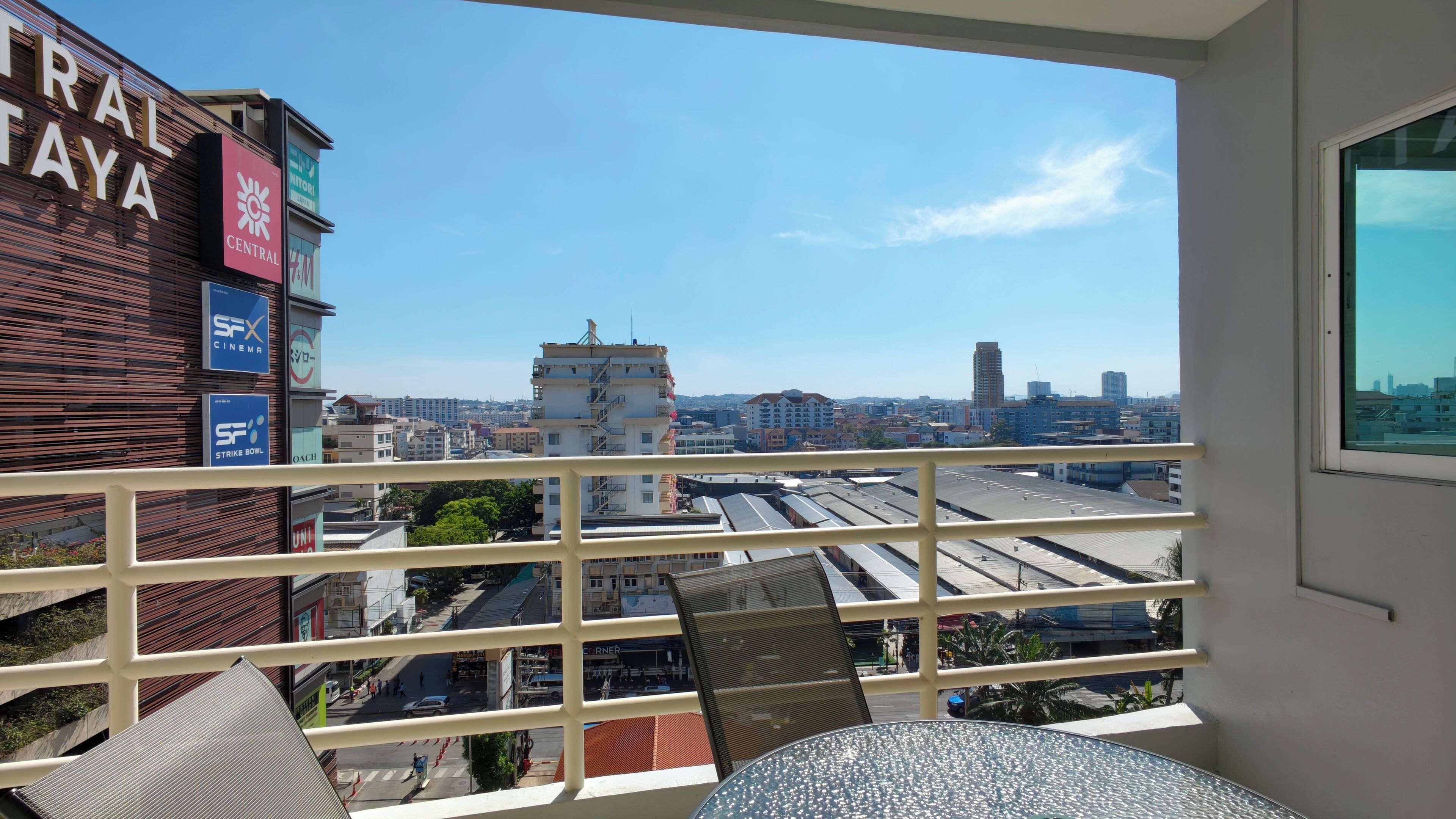 Een balkon met uitzicht op een stadsbeeld, met gebouwen en een heldere lucht.