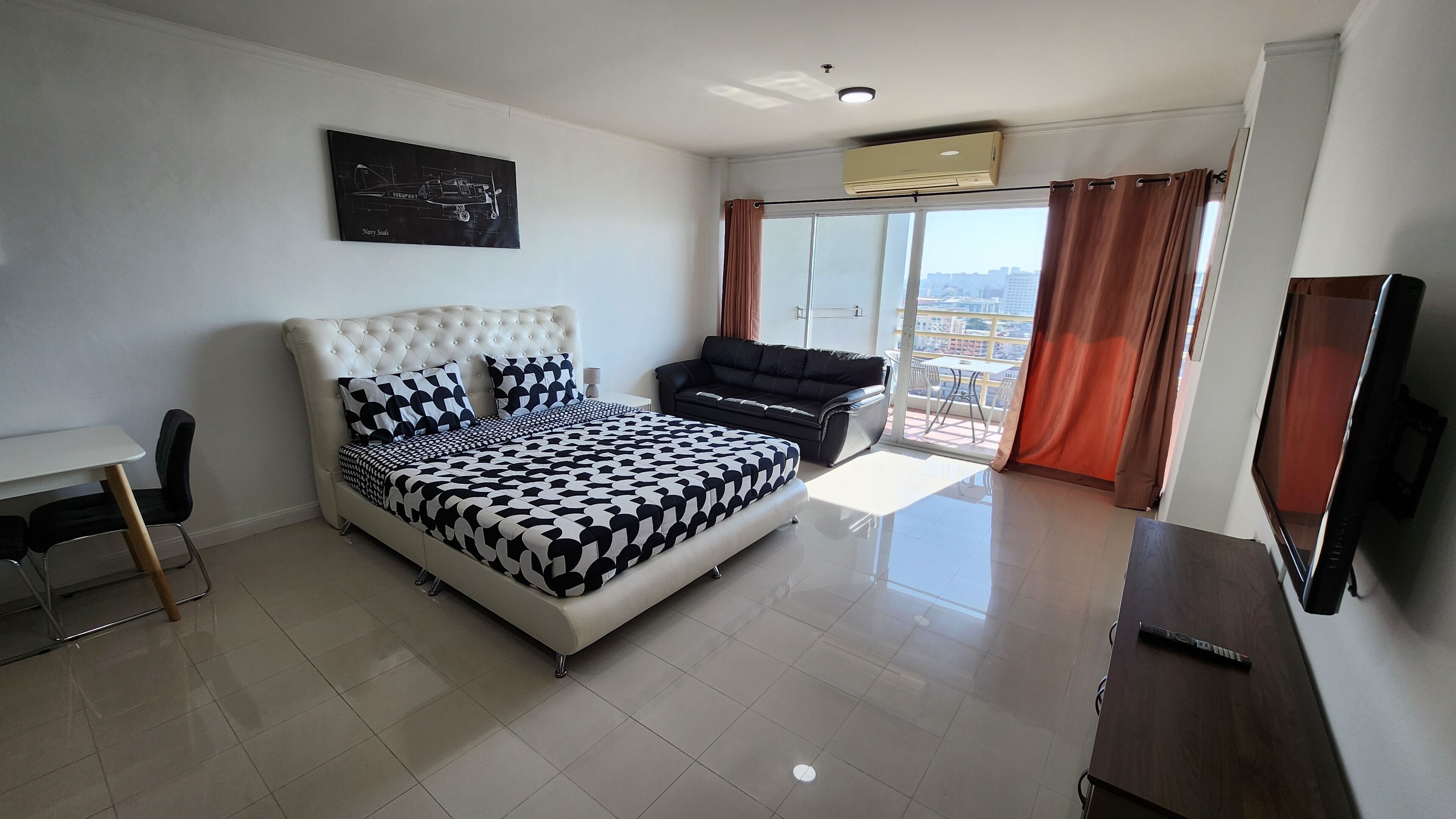 A modern bedroom with a large bed, a sofa, a desk, and a TV.