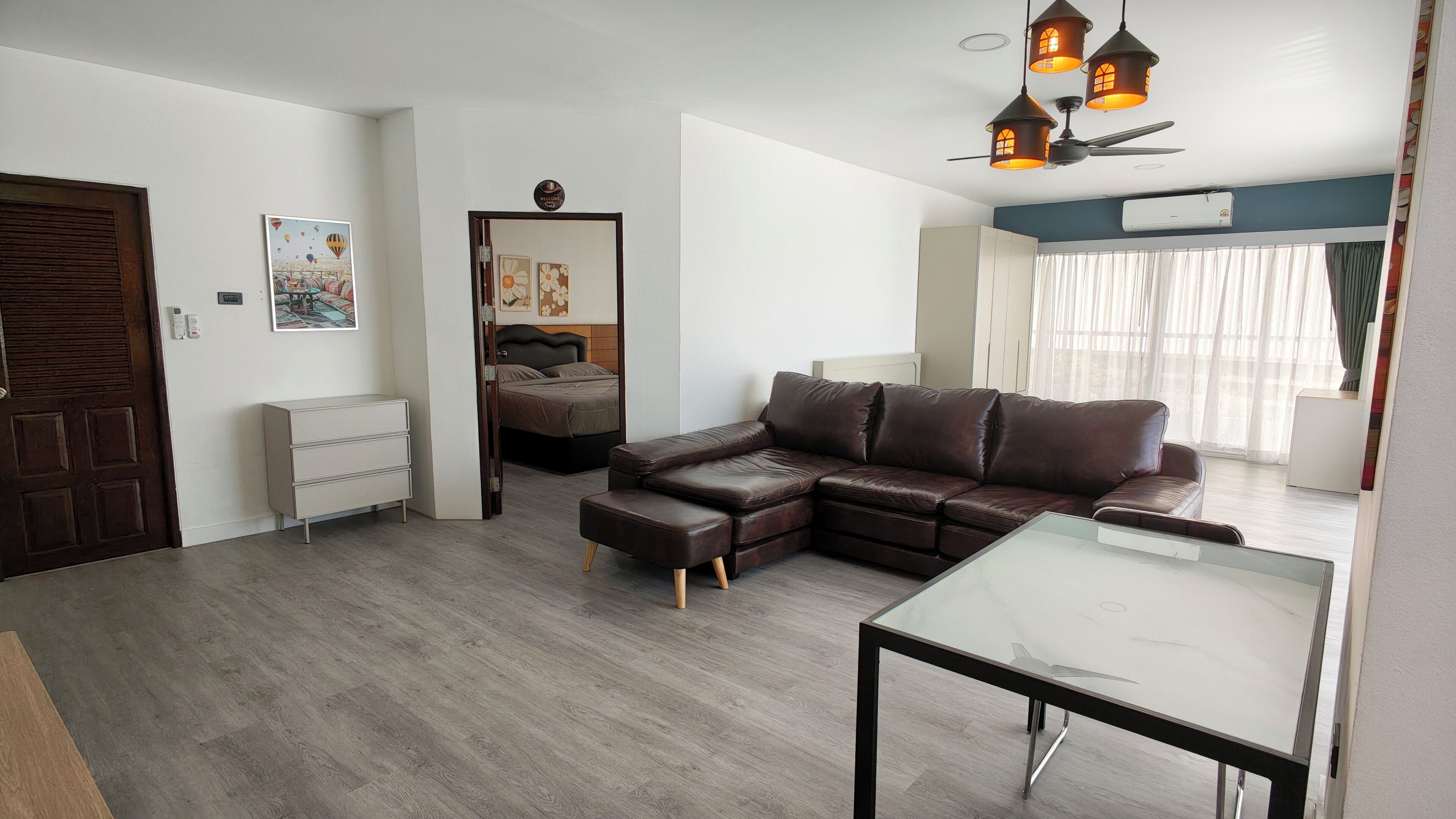 Un salon moderne avec un canapé en cuir, une table basse en verre et un plancher en bois.
