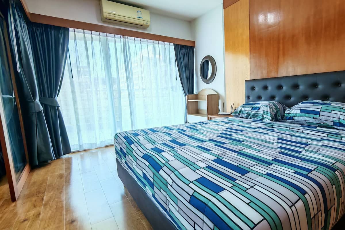 Ein Hotelzimmer mit einem großen Bett, einem hölzernen Kopfteil, einem Schreibtisch und einem Sessel.