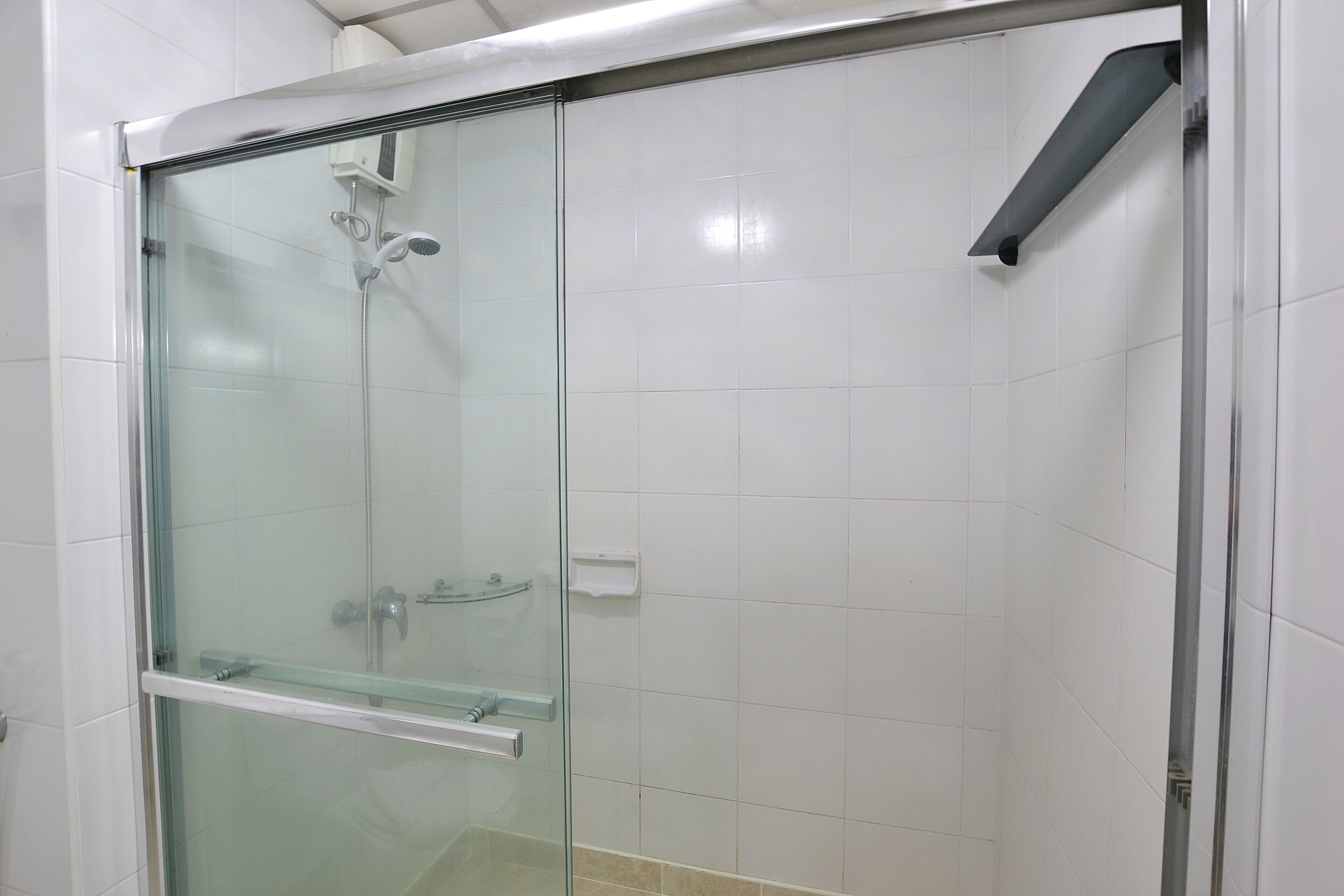 A glass-enclosed shower stall with a handheld showerhead and a wall-mounted faucet.