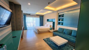 Quarto de hotel moderno com uma cama grande, um sofá, uma TV e uma mesa de trabalho.