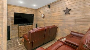 A room with a wooden wall, a flat-screen TV, a leather sofa, and a star decoration.