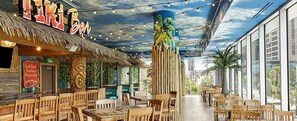 Relax in a tropical oasis with a bar area, thatched roof, and cozy seating for dining or socializing.