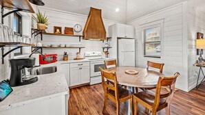 A kitchen with white cabinets, a wooden dining table, and a coffee maker. - Haven| DogFriendly | BEST View | Hot Tub | Luxury (Gatlinburg)