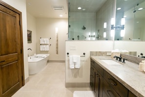 Une salle de bain moderne avec une baignoire, un grand miroir et un meuble-lavabo doté d’un évier et d’un plan de travail.