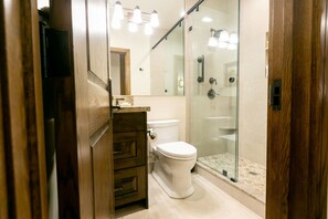Ein modernes Badezimmer mit Duschkabine aus Glas, Toilette und Holzwaschtisch.