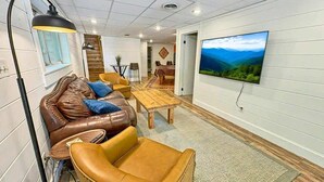 Ein modernes Wohnzimmer mit einer Ledersofa, einem Holztisch und einem flachbildfernseher an der Wand.