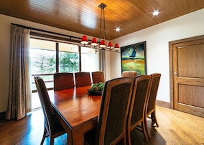 A dining area with a wooden table and chairs, a chandelier, and a painting on the wall.