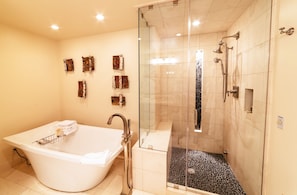 A modern bathroom with a freestanding bathtub, a glass-enclosed shower, and decorative wall art.