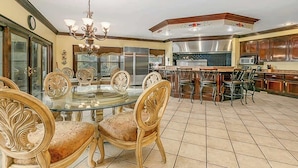 A spacious kitchen with a central island, bar stools, and a dining table with ornate chairs.