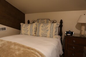 Ein Schlafzimmer mit einem Bett, einem Nachttisch, einer Lampe und einer an der Wand befestigten Uhr.