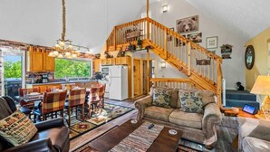 A spacious living area with a wooden staircase, a dining table, and a cozy seating arrangement.