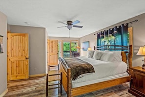 Quarto com cama de madeira, ventilador de teto e vista para o exterior.