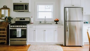 A modern kitchen with white cabinets, stainless steel appliances, a microwave, oven, and refrigerator.
