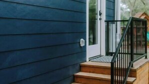 A house with dark blue siding, a white door, and a black railing on the front steps.