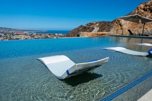 Una piscina infinita con agua azul cristalina, sillones de descanso y vistas a la costa.