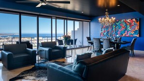 A modern living room with a city view, a chandelier, and a colorful abstract painting. - Greatest view in the world! (Cabo San Lucas)