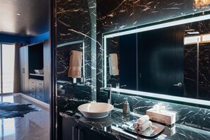 A modern bathroom with a large mirror, black marble countertops, and a sink.