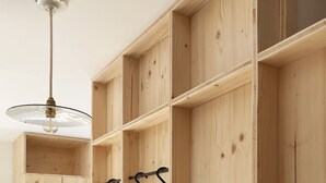 Une pièce avec des étagères en bois, un luminaire suspendu et une petite cage à oiseaux.
