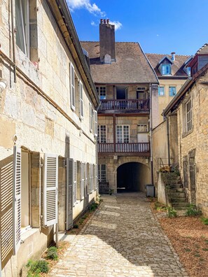 A narrow cobblestone alleyway between historic stone buildings with shuttered windows and a central archway. - Cozy N'est house on historic courtyard-garden, close to station and city center (Besançon)