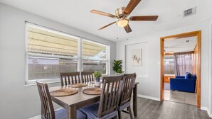 A dining area with a wooden table, chairs, and a ceiling fan.