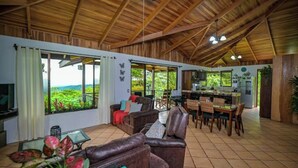 A spacious living area with a high wooden ceiling, a dining table, and comfortable seating. - Casa Bromelia, 30 minutes from La Fortuna (La Tigra)