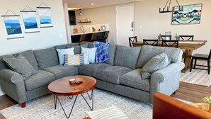 A modern living room with a grey sectional sofa, a wooden coffee table, and a brown leather armchair.