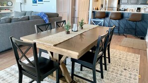 A modern kitchen with dark cabinets, a central island, and a dining area with a wooden table and chairs.