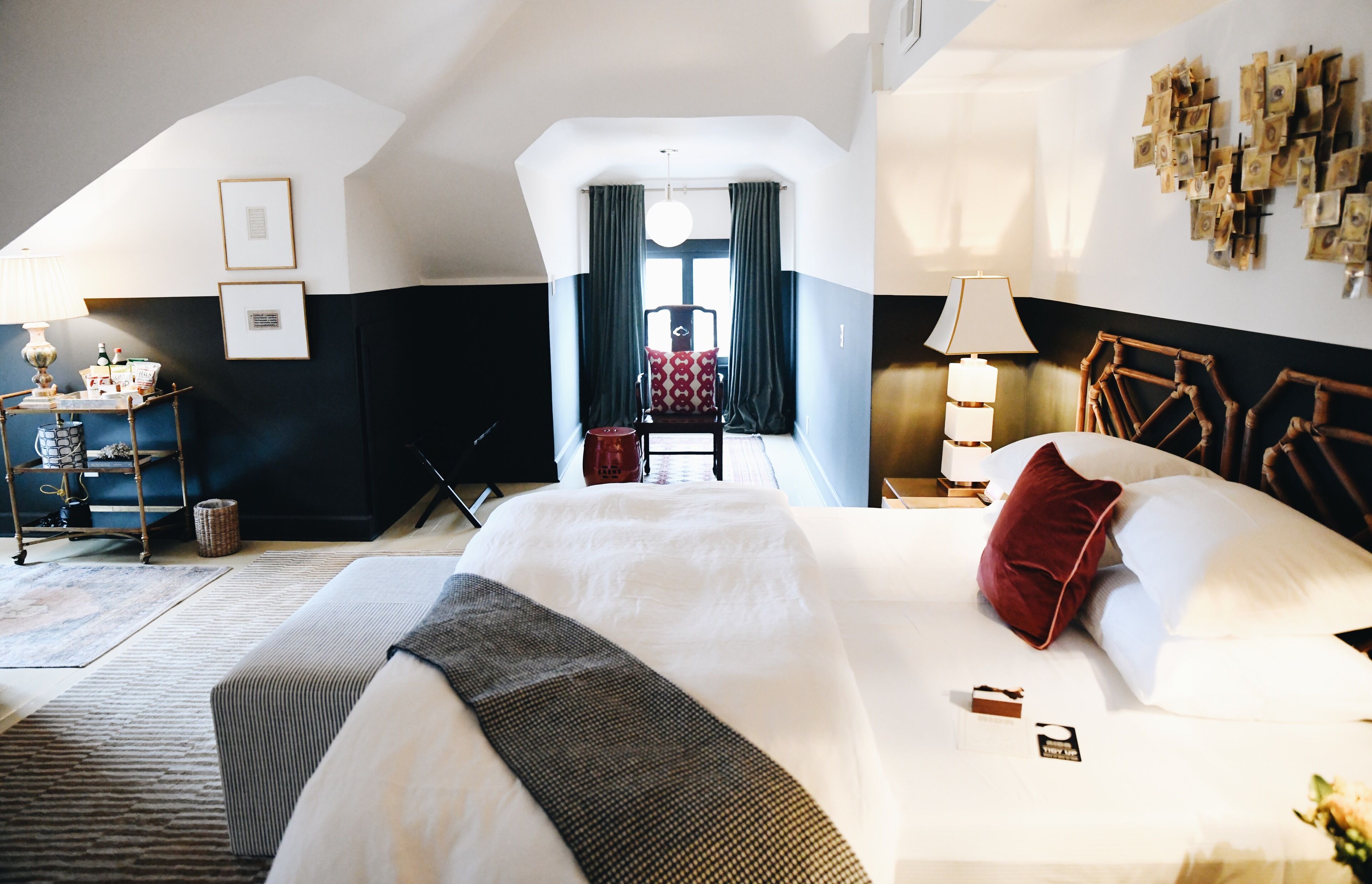 A hotel room with a large bed, a chair, a desk, and a window with curtains.